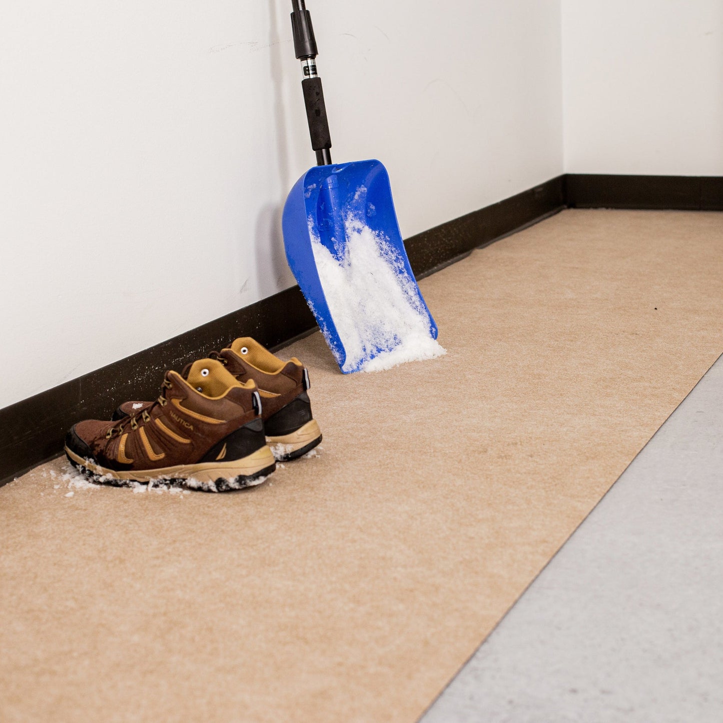Boots and snow shovel on top of Tan Drip & Dry Absorbent Runner