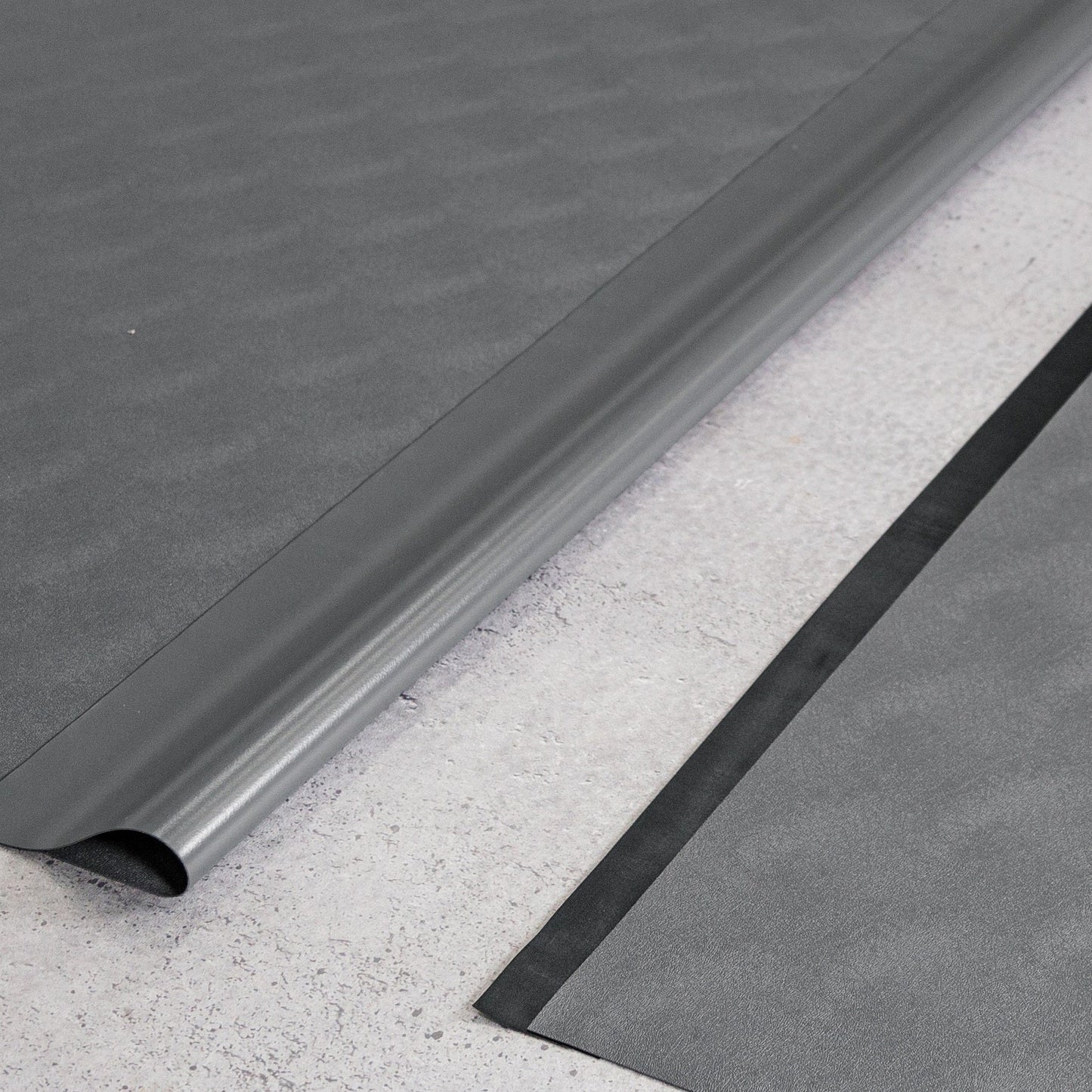 Two pieces of Slate Grey Levant texture vinyl flooring and black seam tape