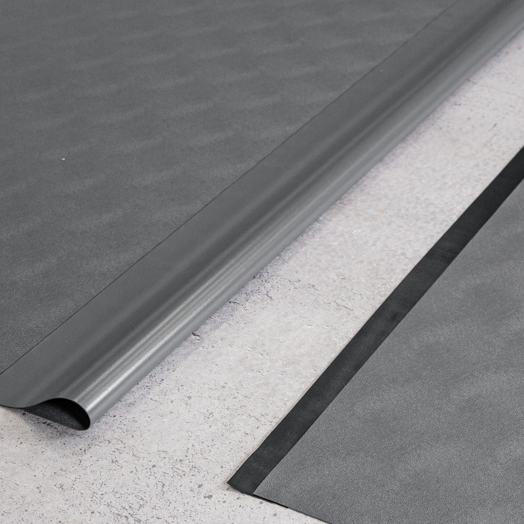 Two pieces of Slate Grey Levant texture vinyl flooring and black seam tape